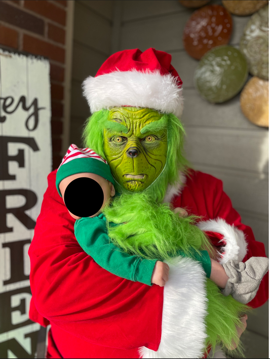 Me dressed as the grinch posing with my friends' newborn.